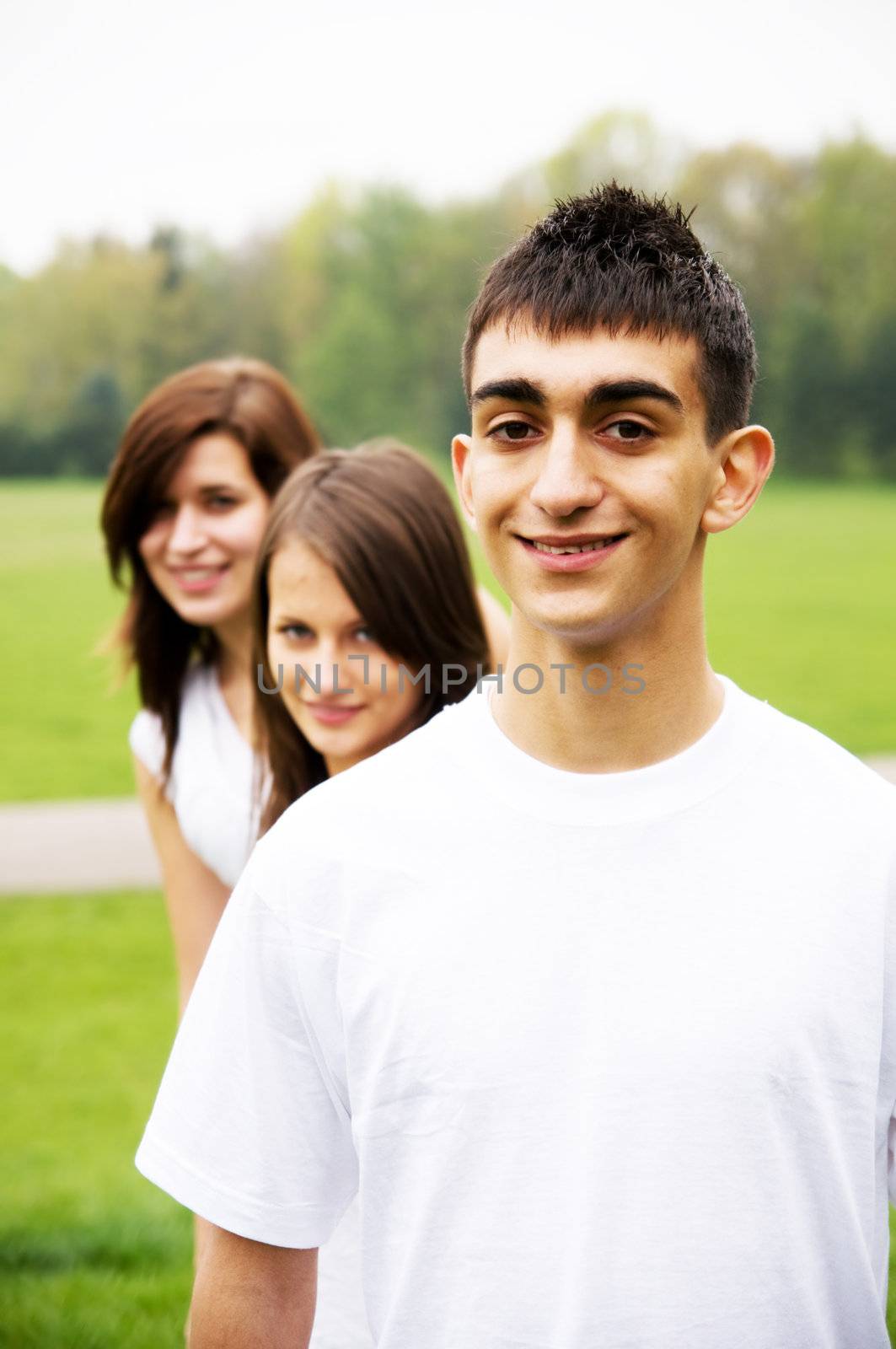 Group of teenagers standing and smiling. Boy in the foreground