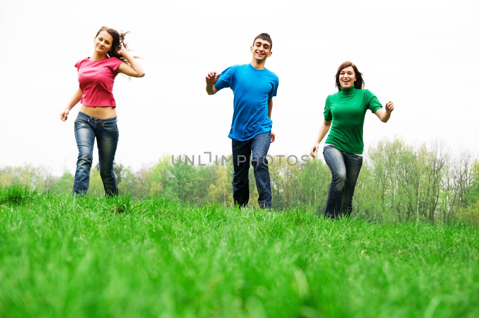 Three happy friends having fun on the spring meadow