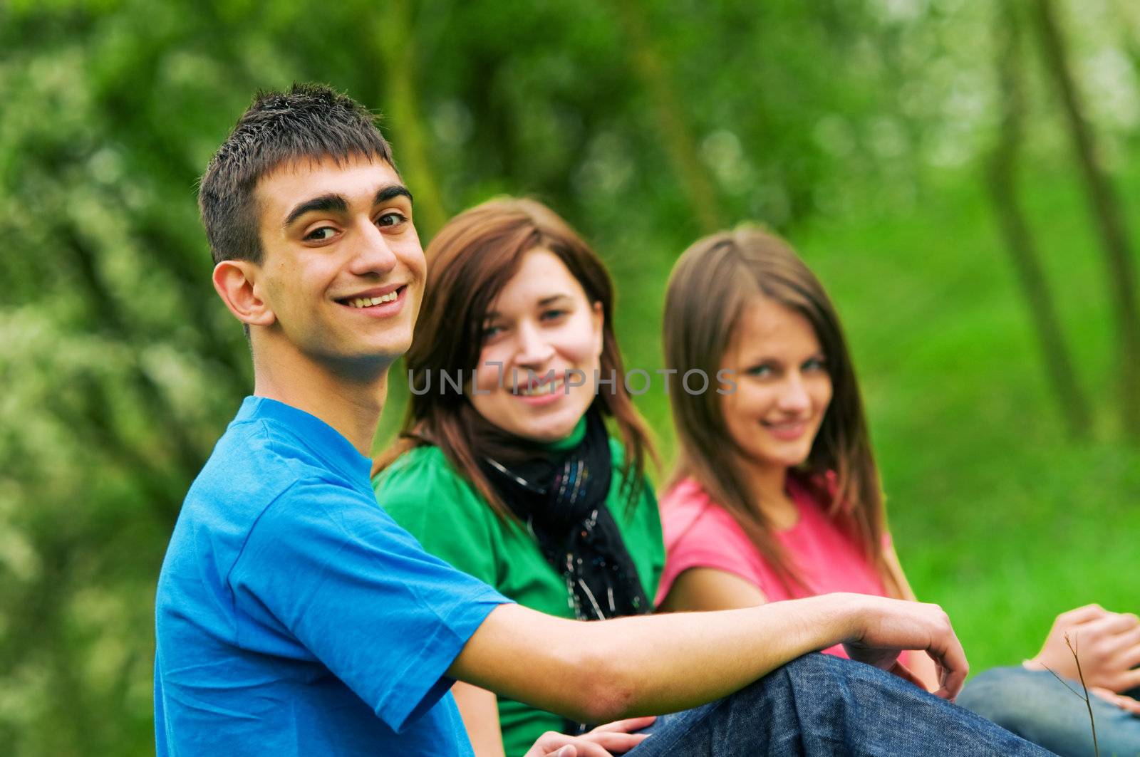 Three young happy friends lying together and smiling