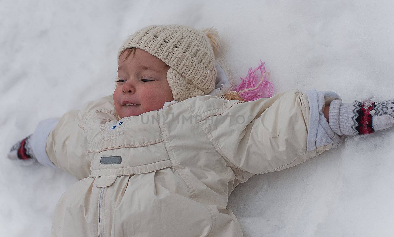 Little girl lays on the snow