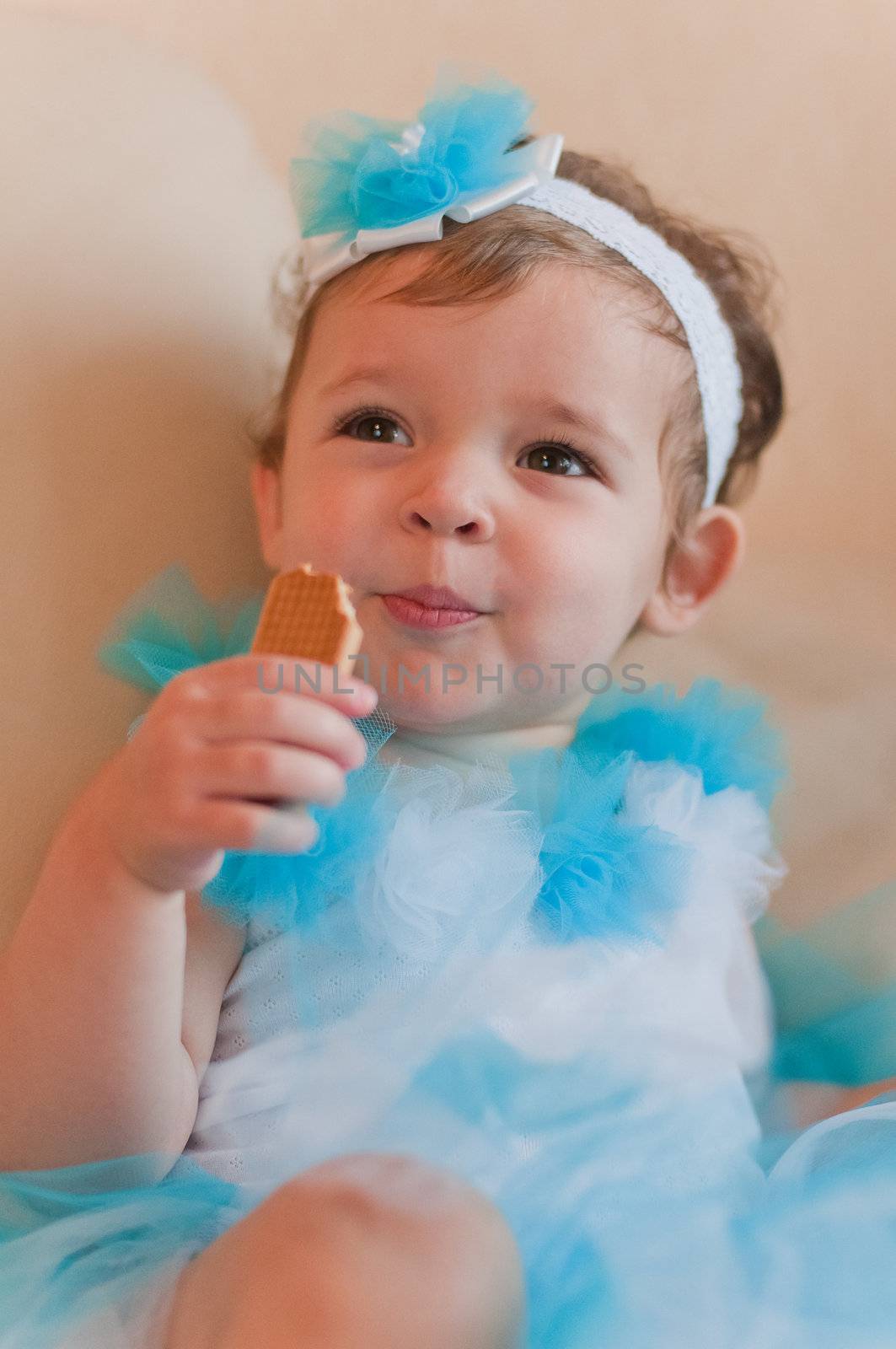 Little girl in the blue dress eats cookie