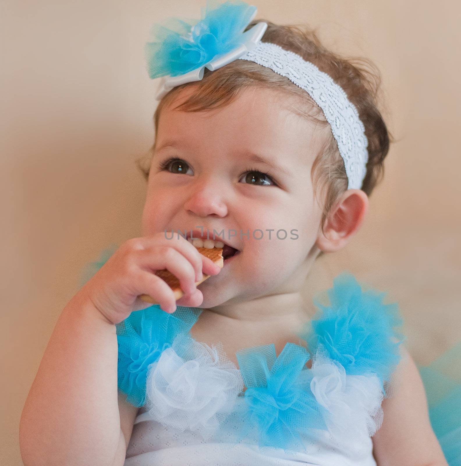 Little girl in the blue dress eats cookie