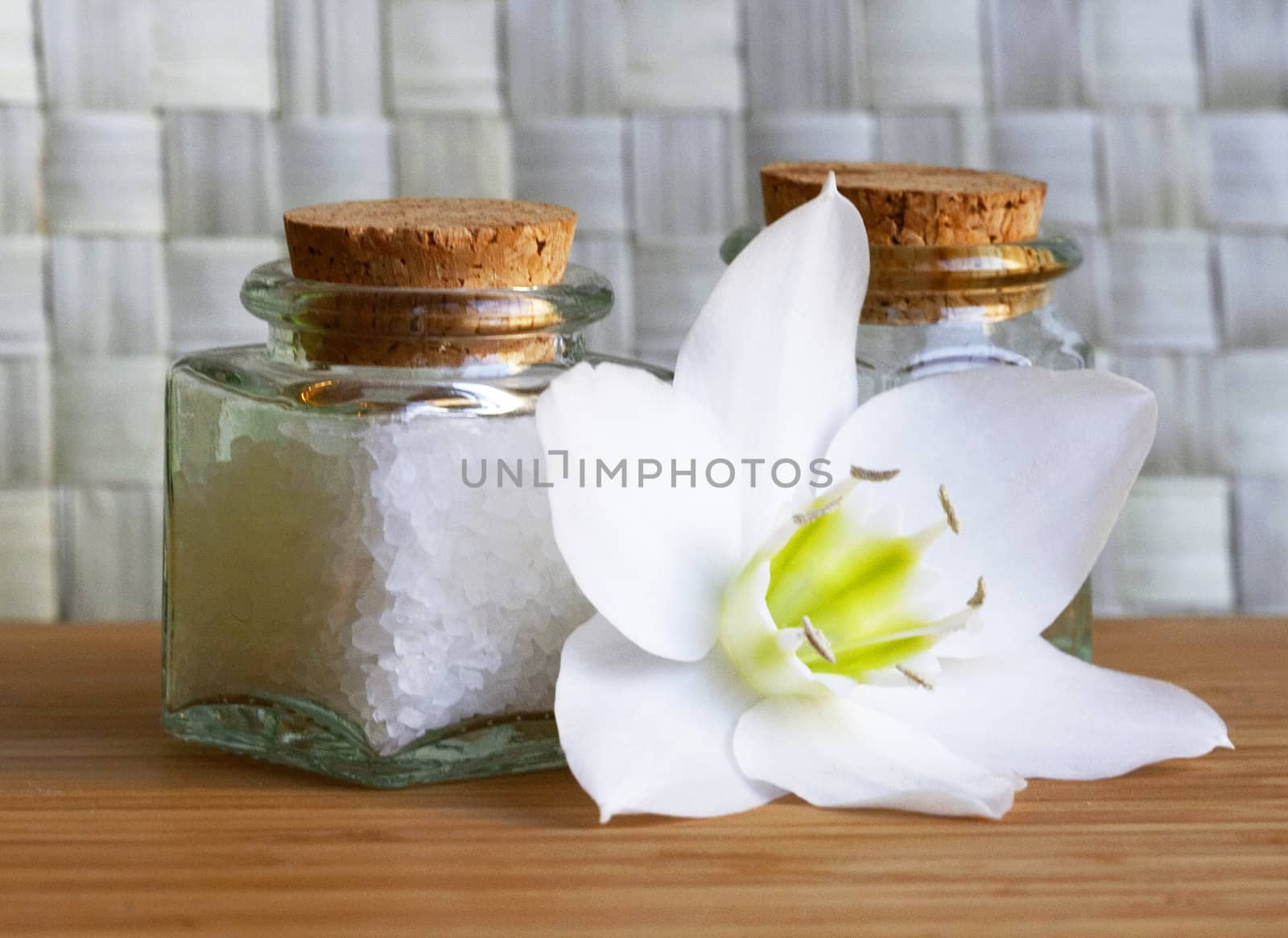 Bottles of sea salt and oil with white flower in spa composition 
