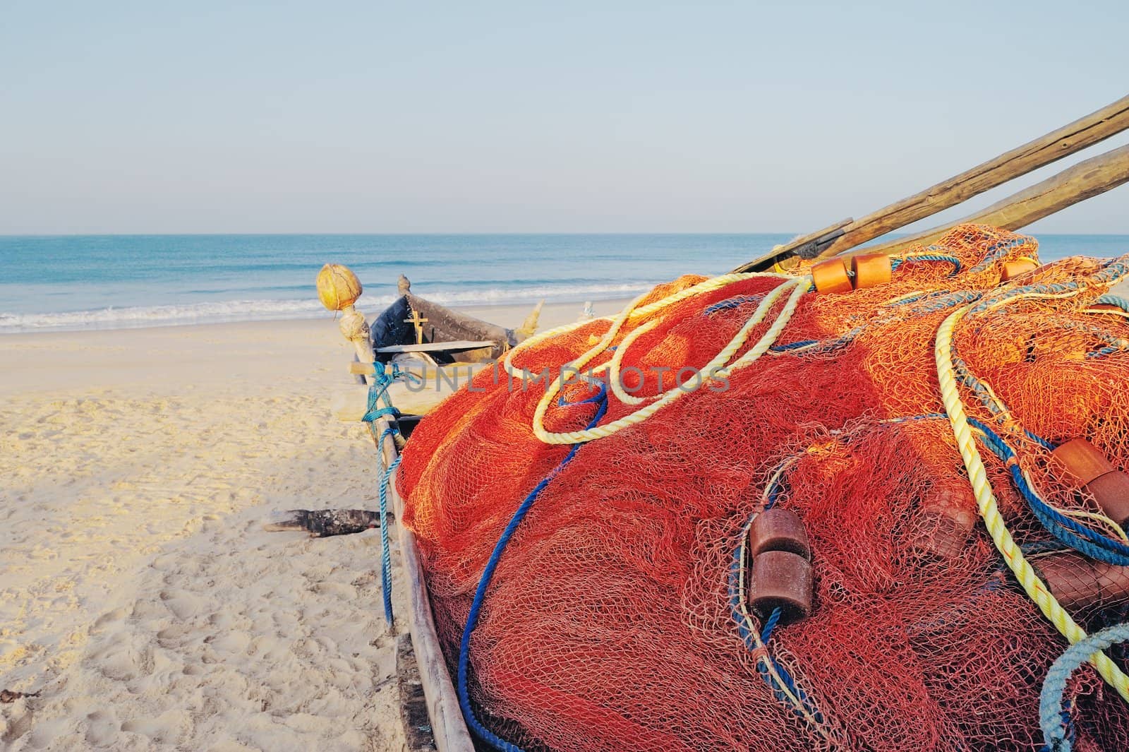 Old boat with fishing net on sandy shore. In Goa