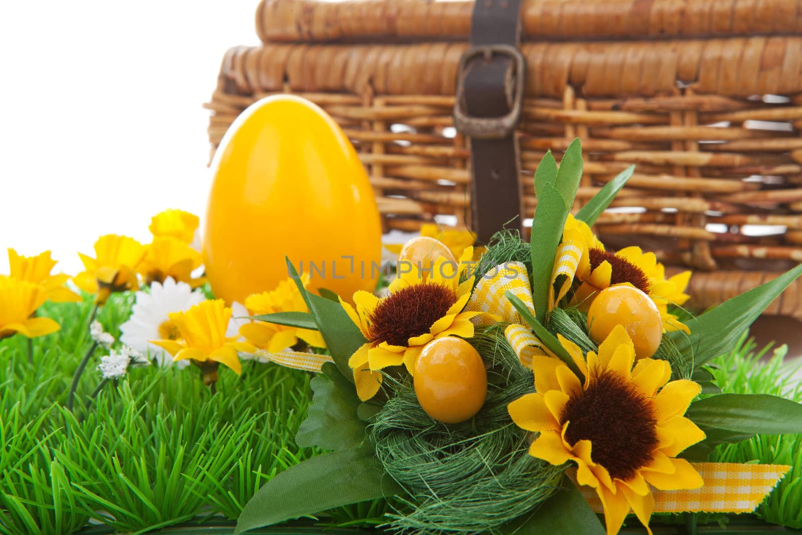 Yellow easter egg and basket on green grass with flowers