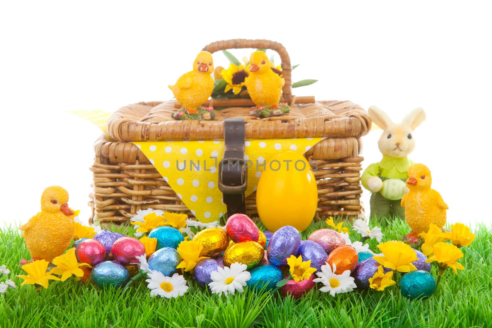 Colorful easter eggs, bunny, chickens and basket on green grass with flowers