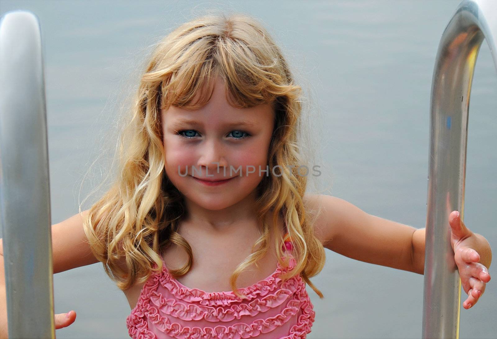 A young girl on a ladder ready to enjoy a swim.