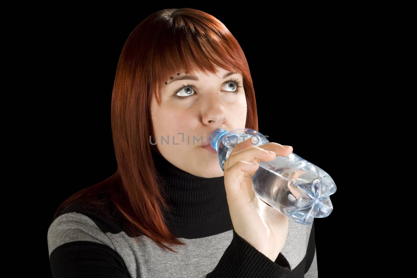 Beautiful girl with red hair drinking water, thirsty.

Studio shot.