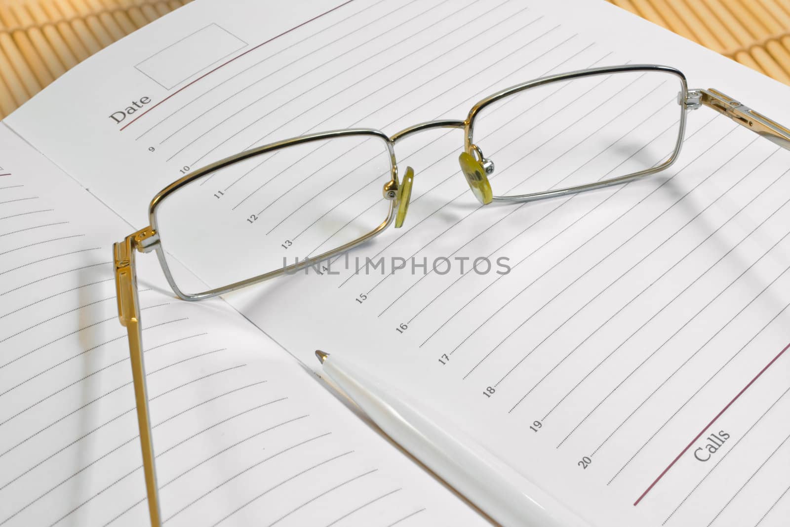 Glasses, pen and notebook, photographed close up.