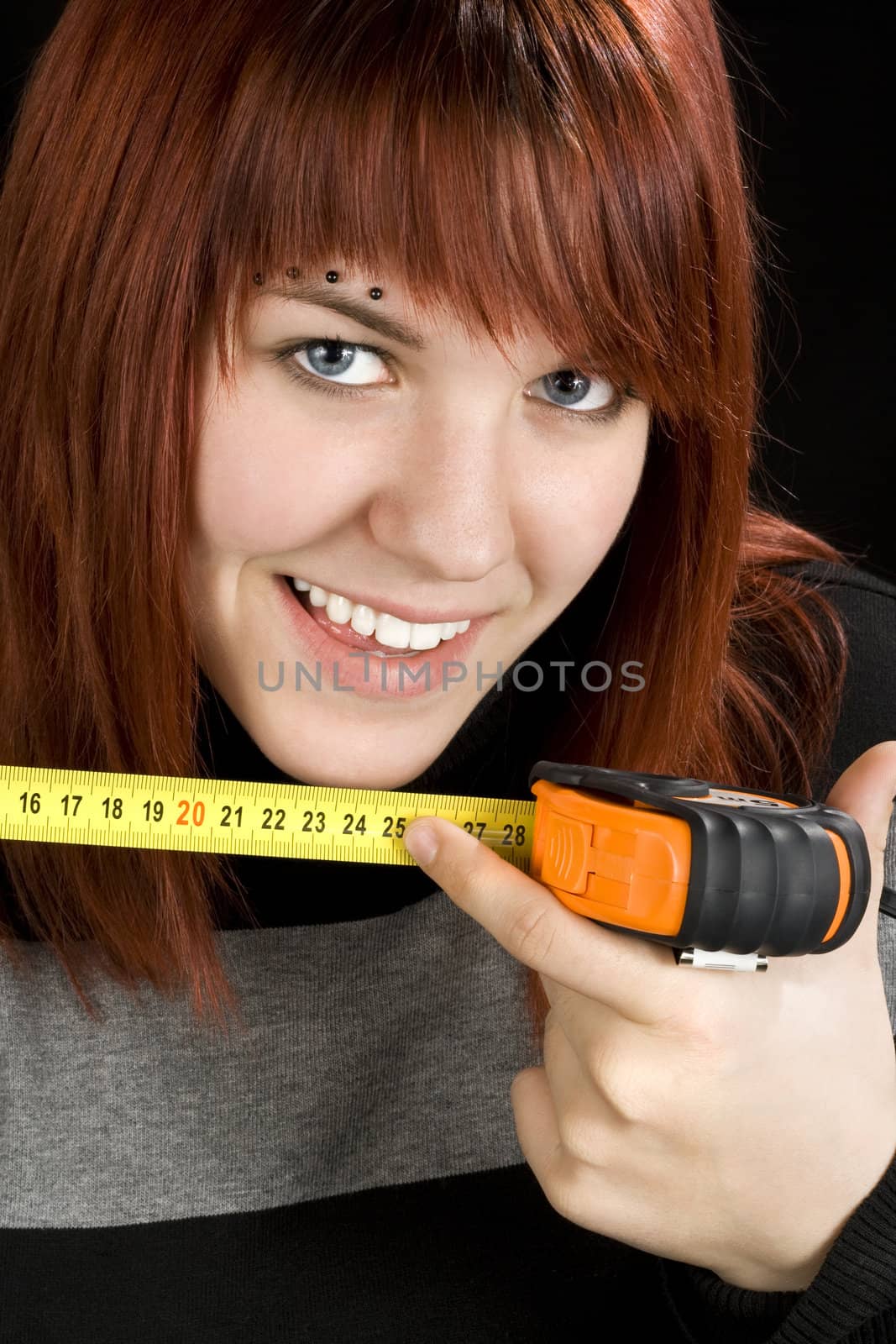 Beautiful redhead girl pointing at 25cm length and smiling. Concept allusion at male organ (penis) length.

Studio shot.