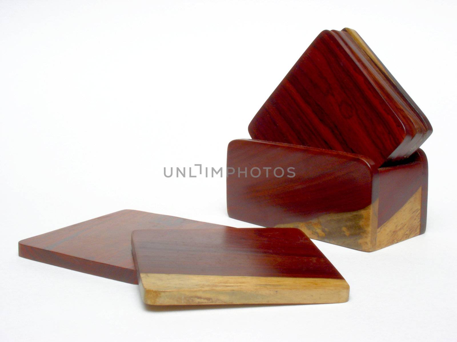 A set of 6 coasters and their holder, made of Costa Rican rosewood, standing on a plain white backdrop. The coasters are mostly reddish-tan in color, but have some tan-colored accents. Four of the coasters are in their holder, with the remaining two arranged in front and to the left of it.