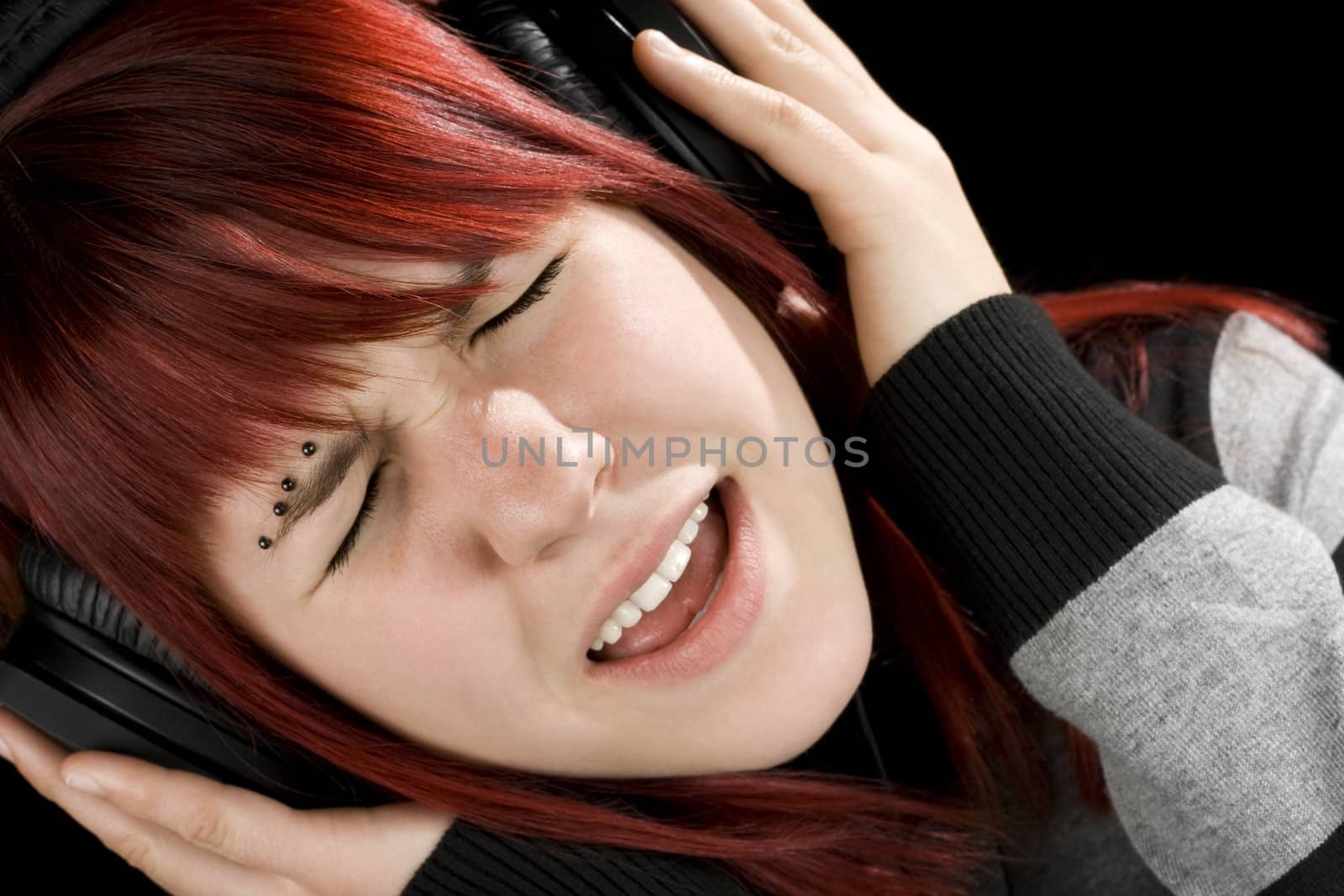Beautiful redhead girl singing while listening to her favorite music.

Studio shot.