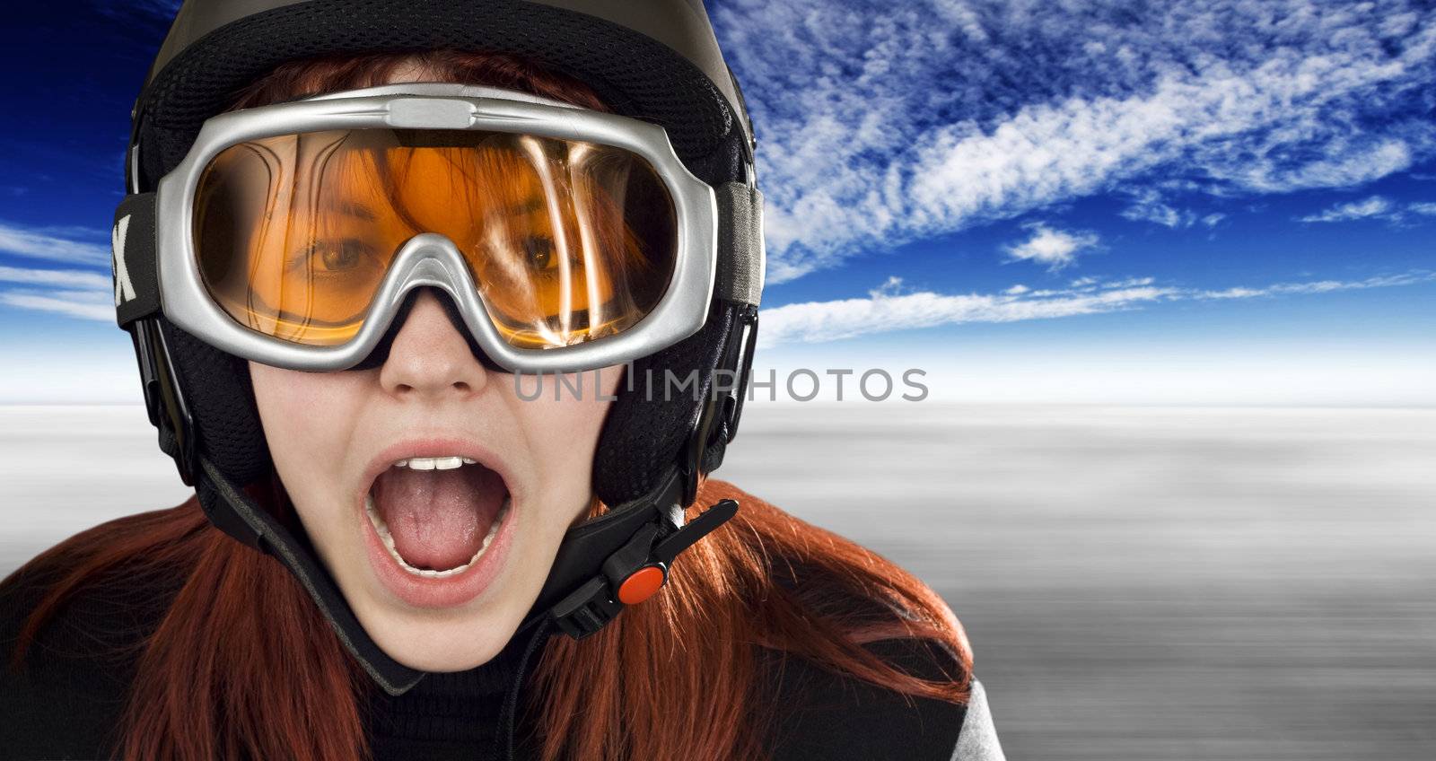 Cute girl with red hair wearing a ski helmet and orange goggles acting surprised and yelling. Feeling cold.

Studio shot.
