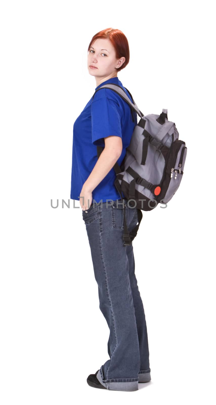 Young redheaded girl with a backpack standing up against a white background.
