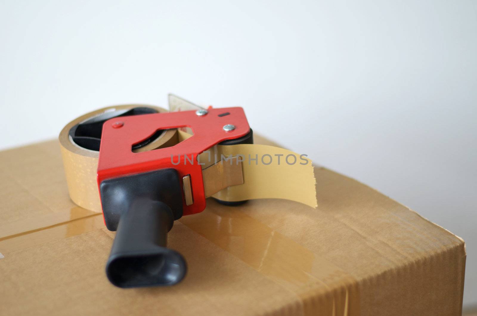 Self-adhesive tape dispenser on brown cardboard box