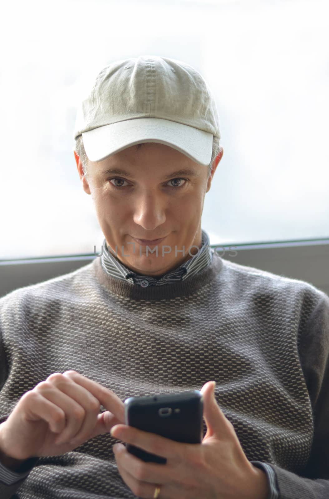 Attractive young man typing on smartphone by artofphoto