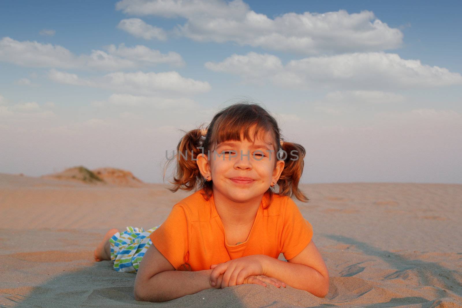 happy little girl lying on beach