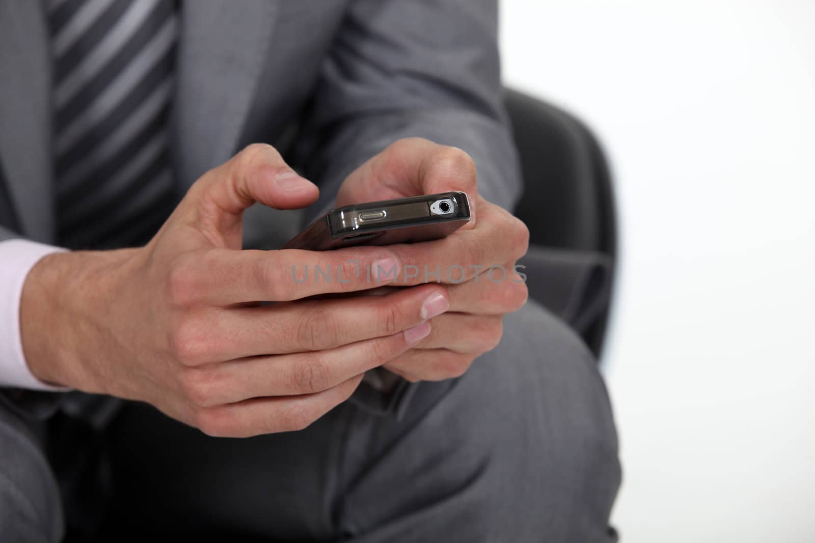 businessman typing on his cell phone by phovoir