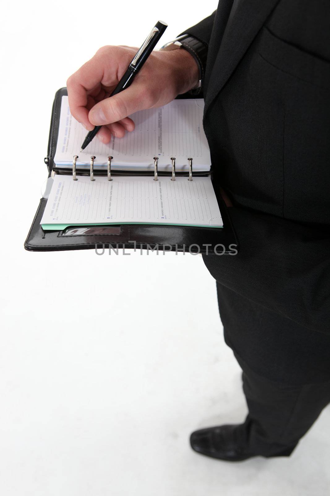 Businessman writing in agenda by phovoir