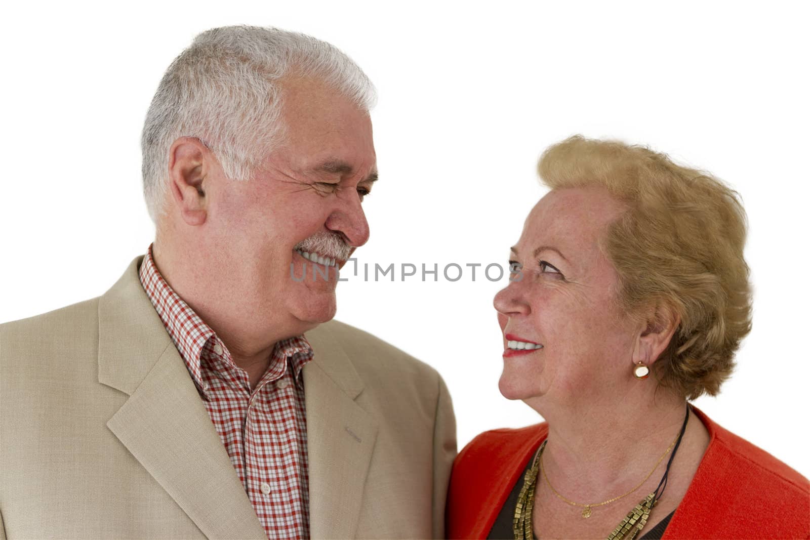 Senior couple looking at eachother trustfully and happly both toothy smiling.