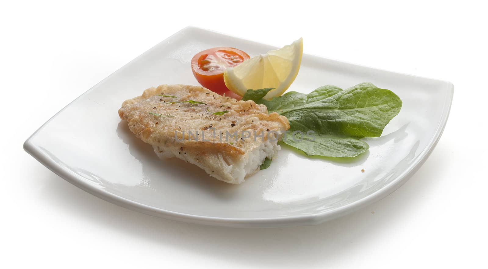 Fried fillet of tilapia with lettuce, lemon and tomato on the white plate