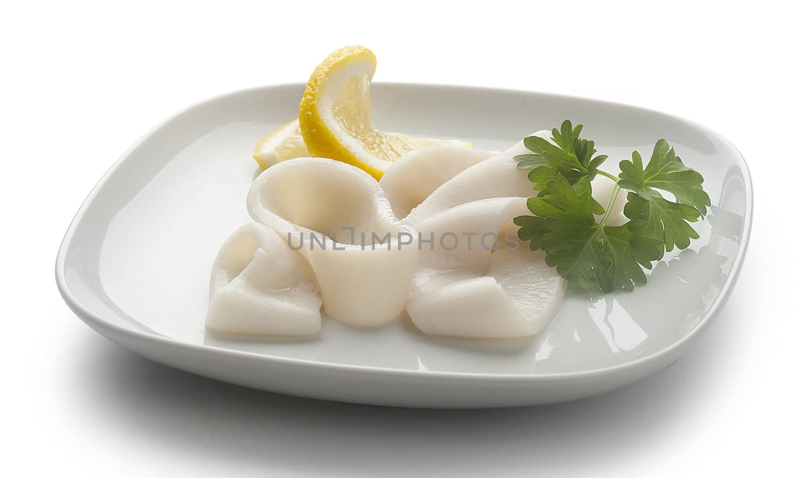 Some raw rings of squid with parsley and lemon on the white plate
