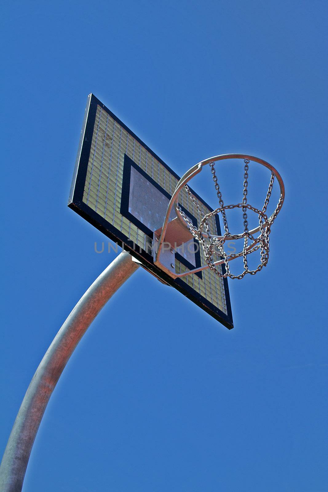 Showing a basketball hoop infront of a bright blue sky.