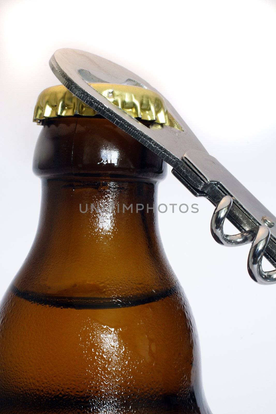 An ice cold beer and a bottle opener. All isolated on white background.