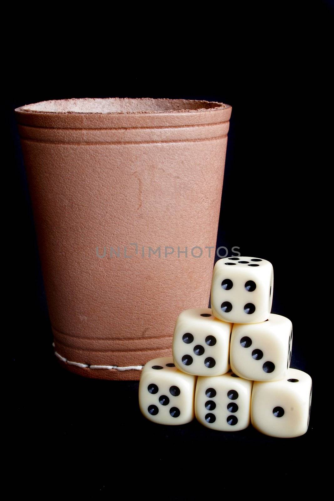 A dice shaker and several dices. All on a plain black background.