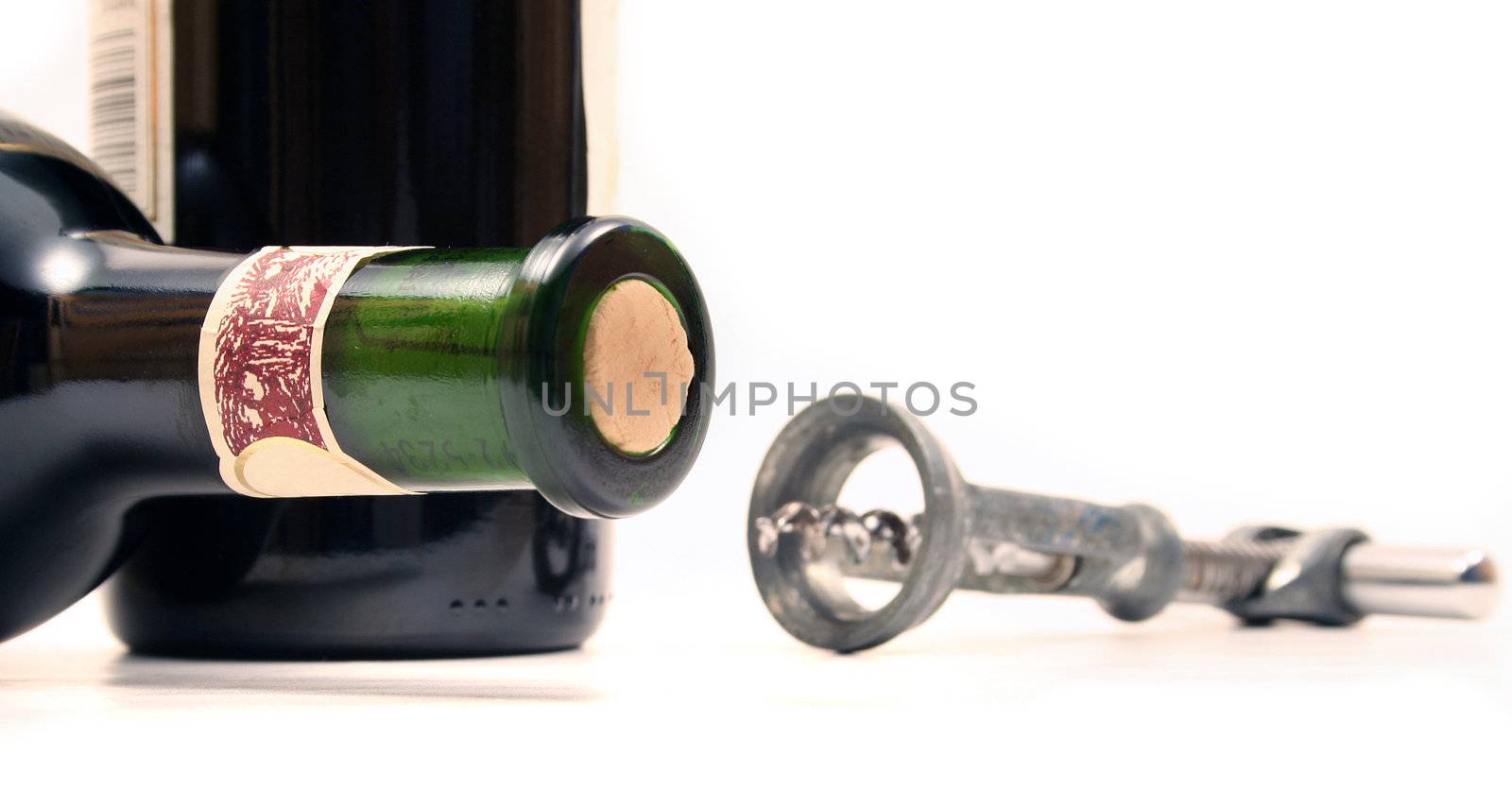 A bottleneck laying next to a bottle opener. All isolated on white background.