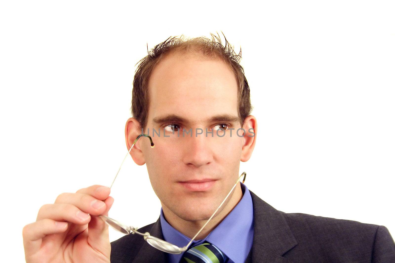 Young businessman holding eyeglasses in hand wearing business suit and tie white background.