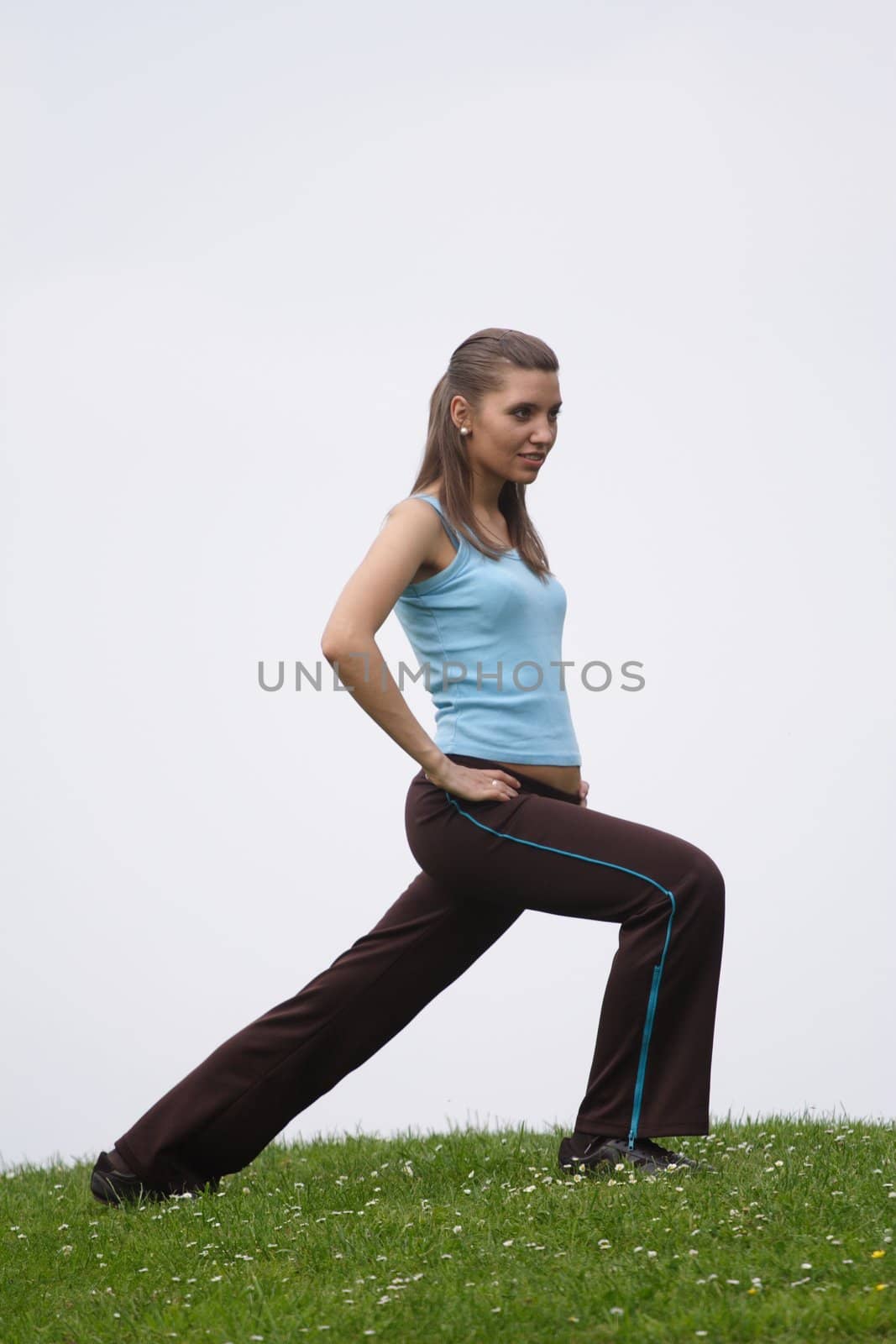 A handsome young woman doing gymnastics on a green meadow. ** Note: Slight blurriness, best at smaller sizes.