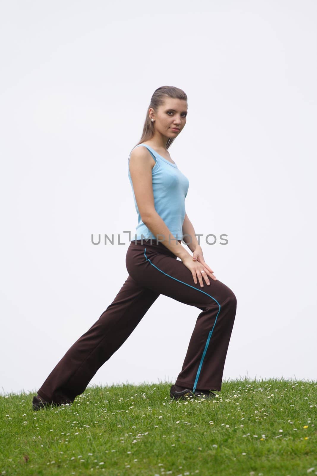 A handsome young woman doing gymnastics on a green meadow. ** Note: Slight blurriness, best at smaller sizes.