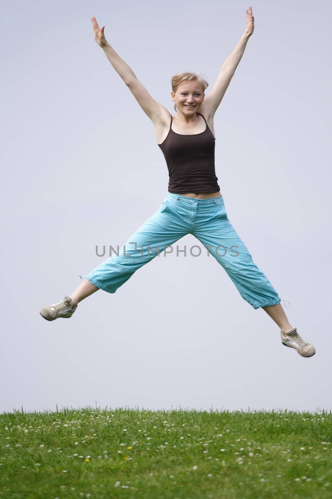 A happy young woman doing sports on a meadow.