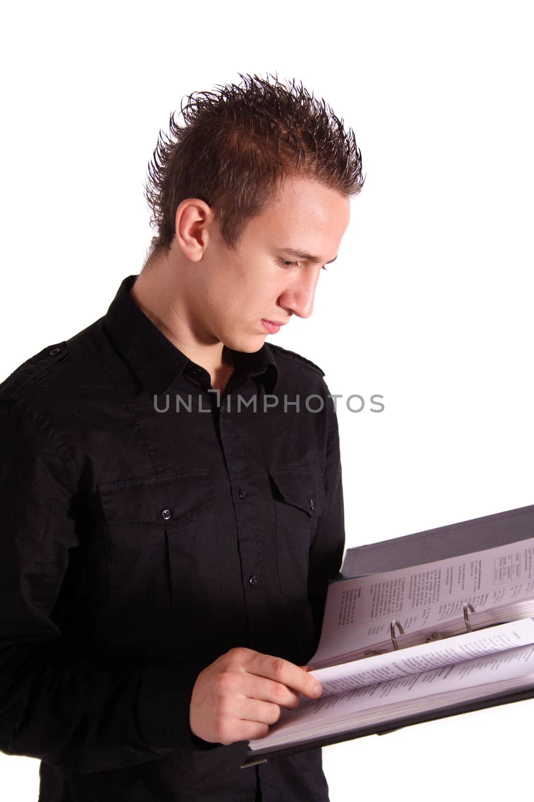 A young handsome student standing in front of a white background reading in his documents.