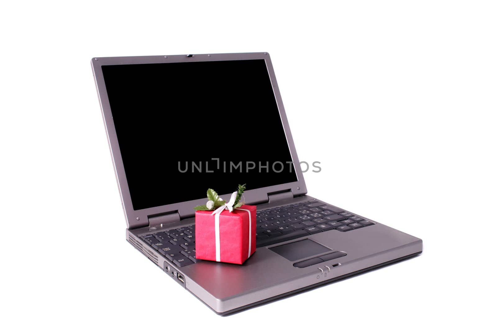 A small red present lying on a notebook computer. All isolated on white background.