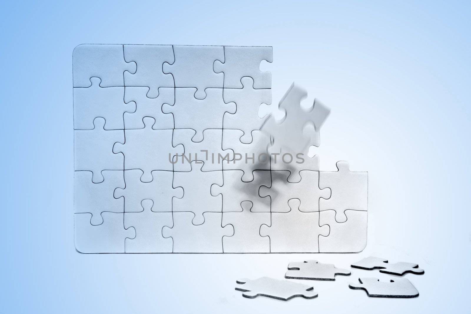 A jigsaw puzzle with various missing pieces. All in front of light blue background.