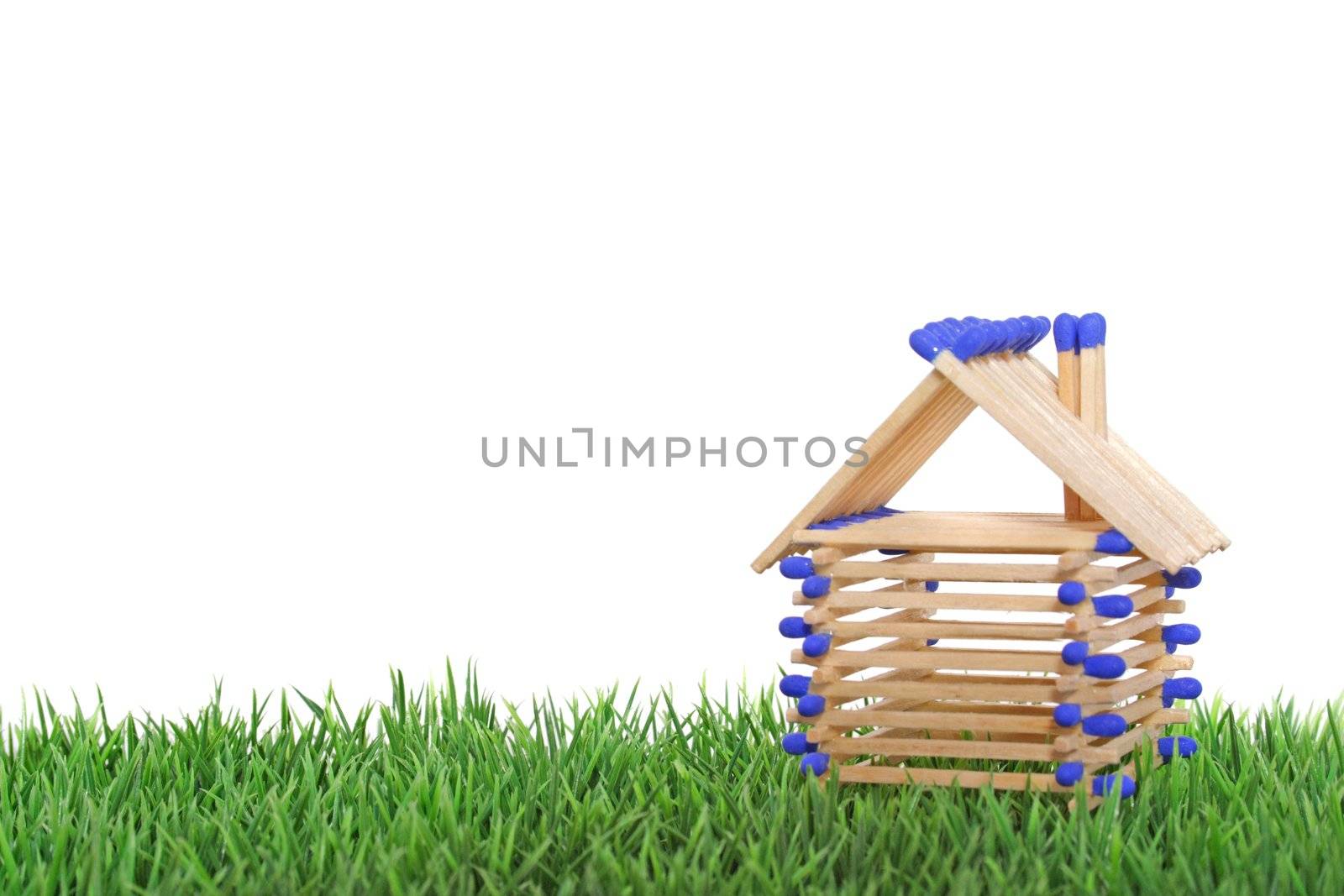 A stylized house out of blocks between blades of grass. All isolated on white background.