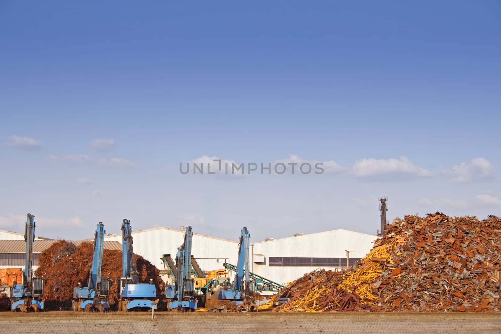 A typical junkyard in front of a shiny blue sky.