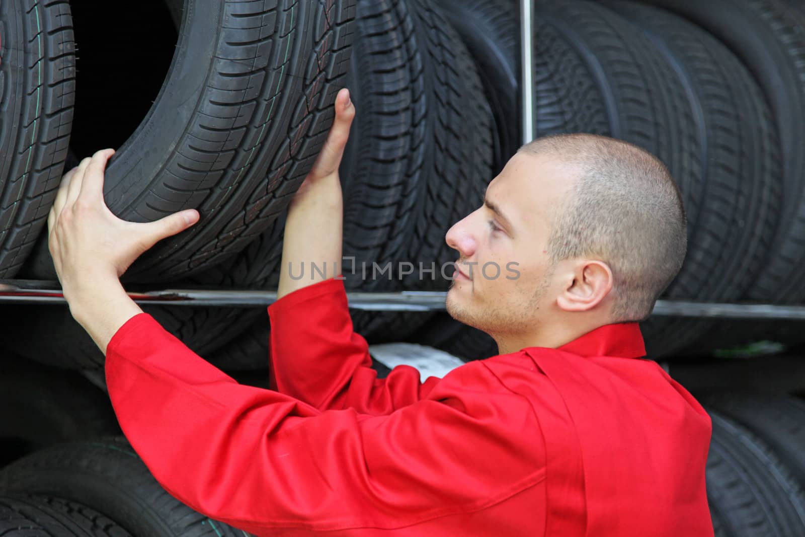 A working mechanic in a garage putting a tire in a rack.