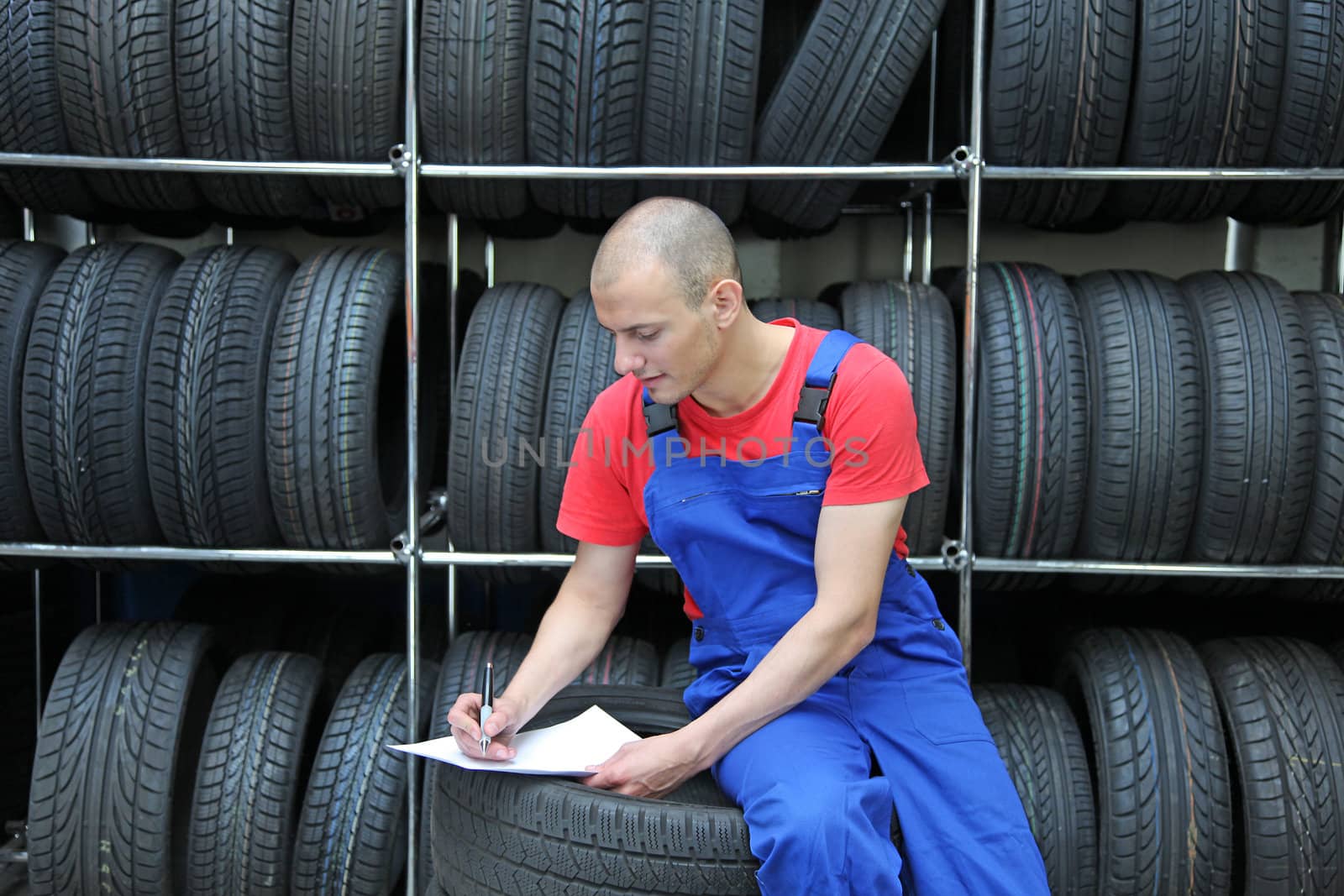 A worker takes inventory in a tire workshop and checks the stock.