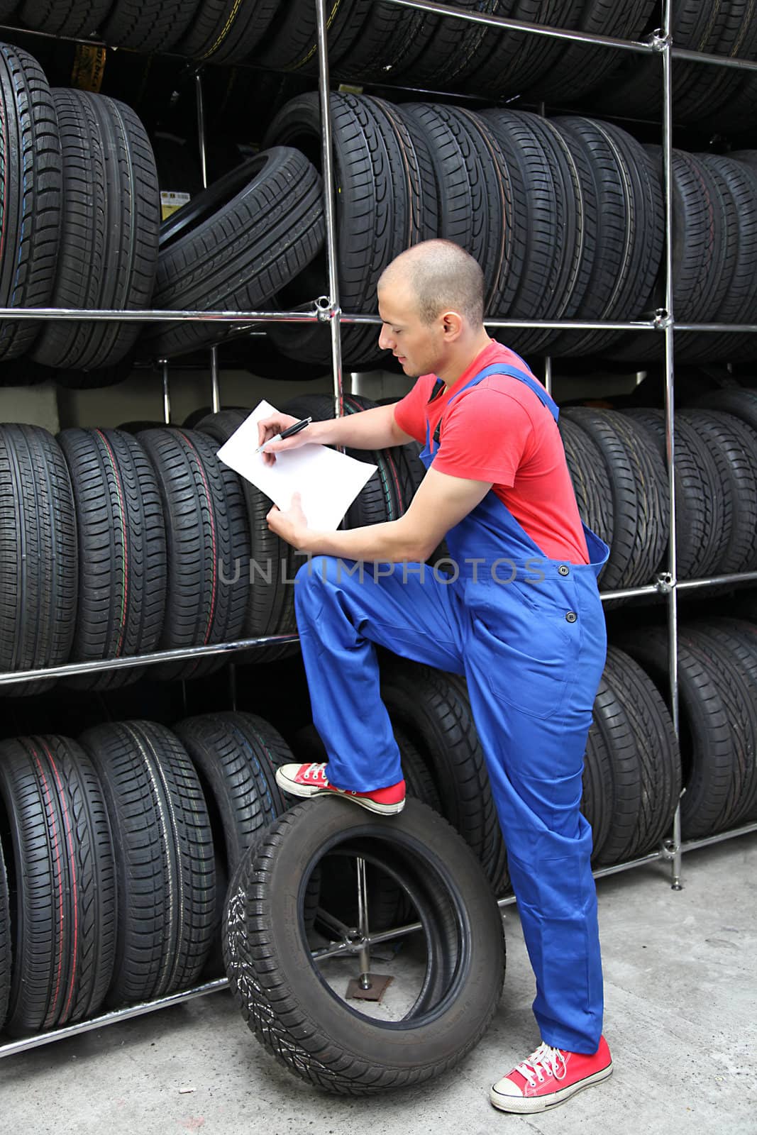 A worker takes inventory in a tire workshop and checks the stock.