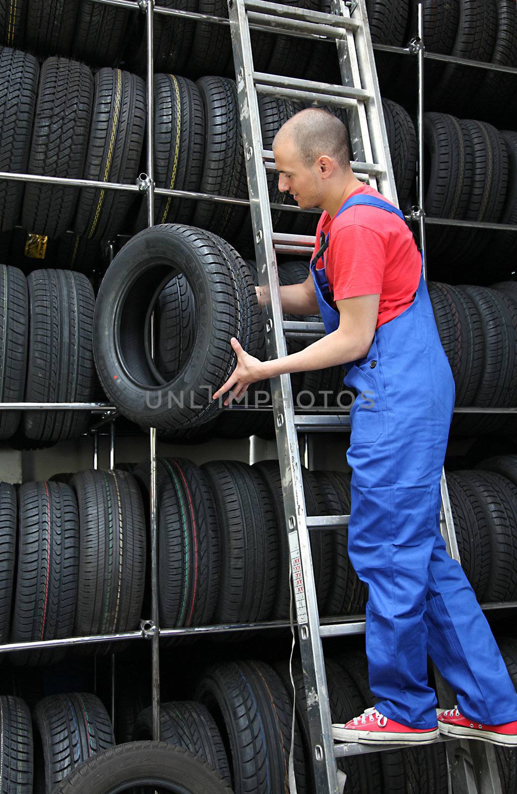 A motivated worker in a tire workshop restocking the goods.