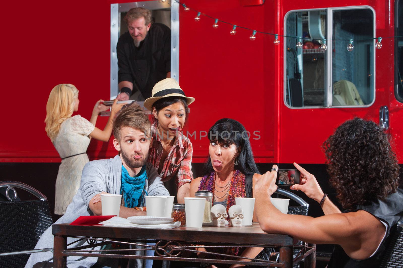 Friends sticking out tongues for photo near food truck