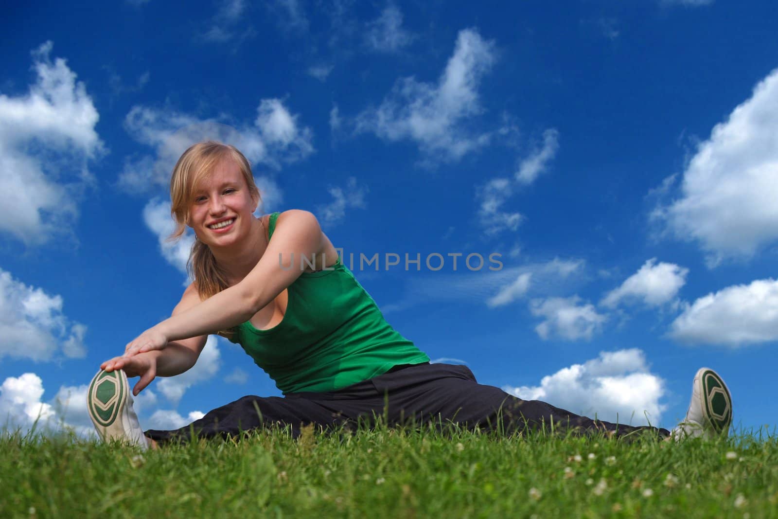 On a summery day a sporty girl is doing exercises outside.