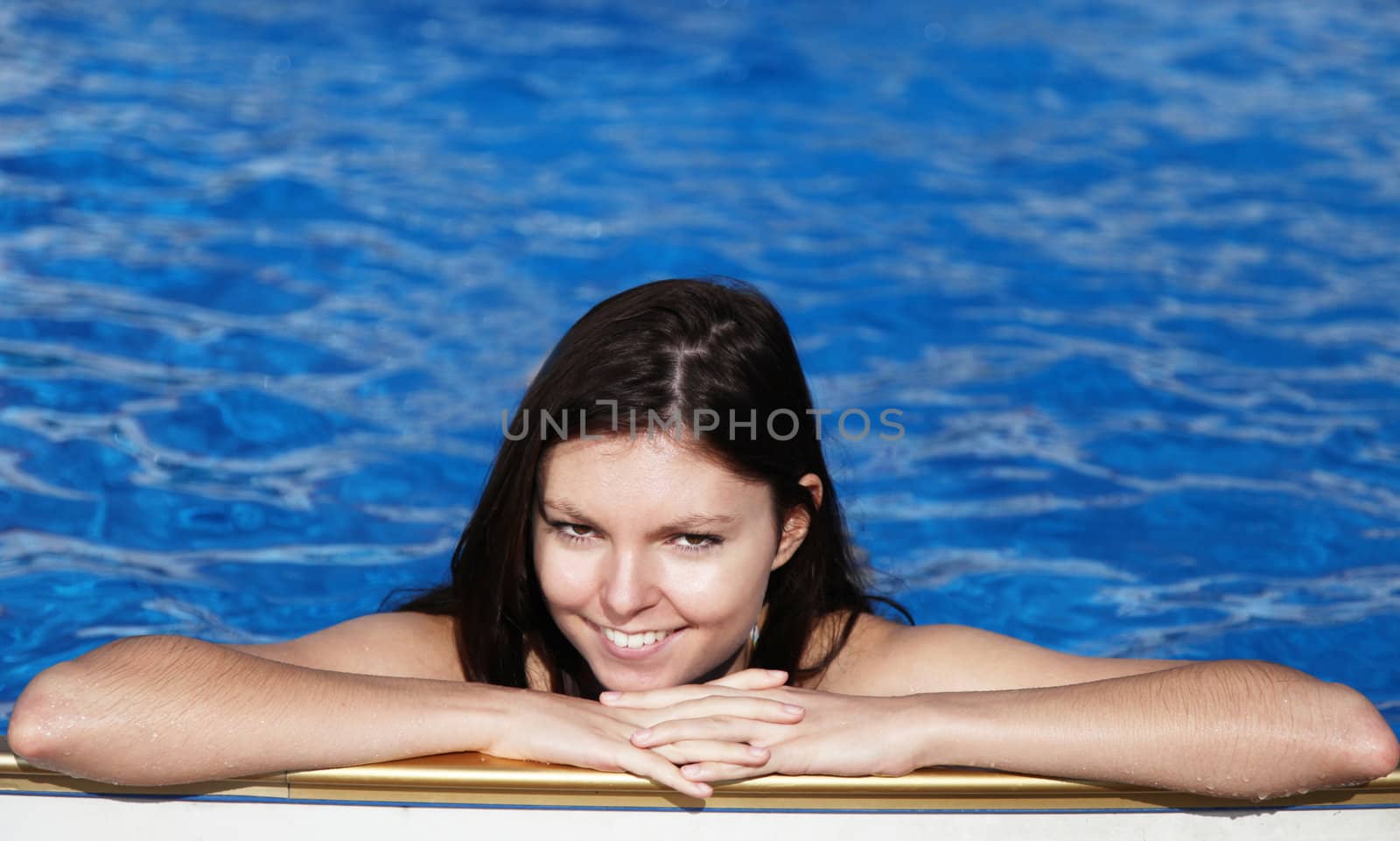 A very attractive young woman refreshing in a swimming pool.