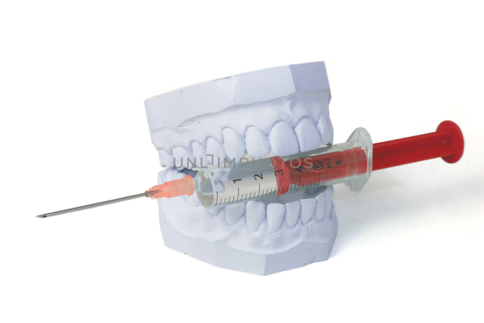 A plaster cast of a set of teeth bites into a syringe. All isolated on white background.
