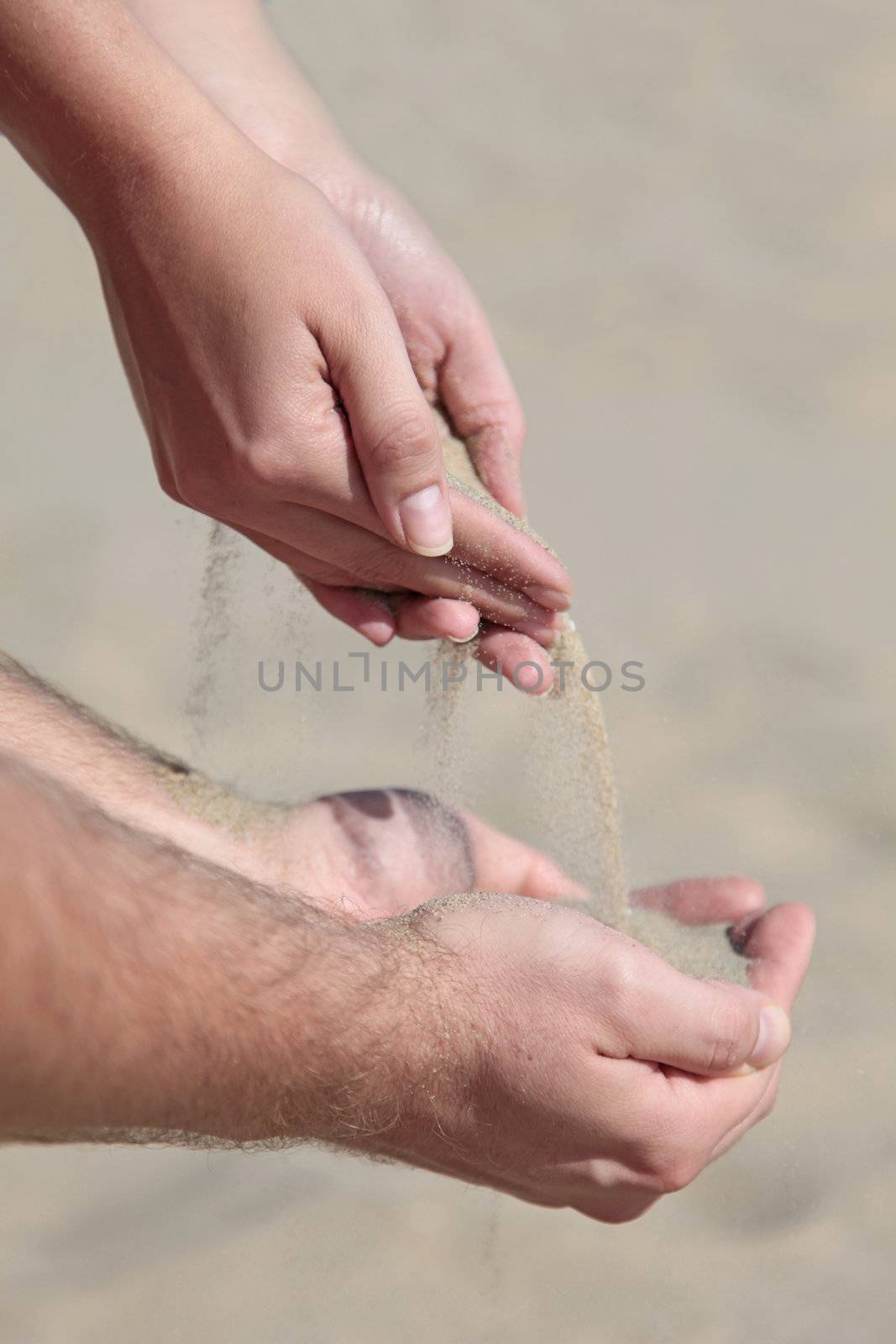 A person holding dry sand in his hands.