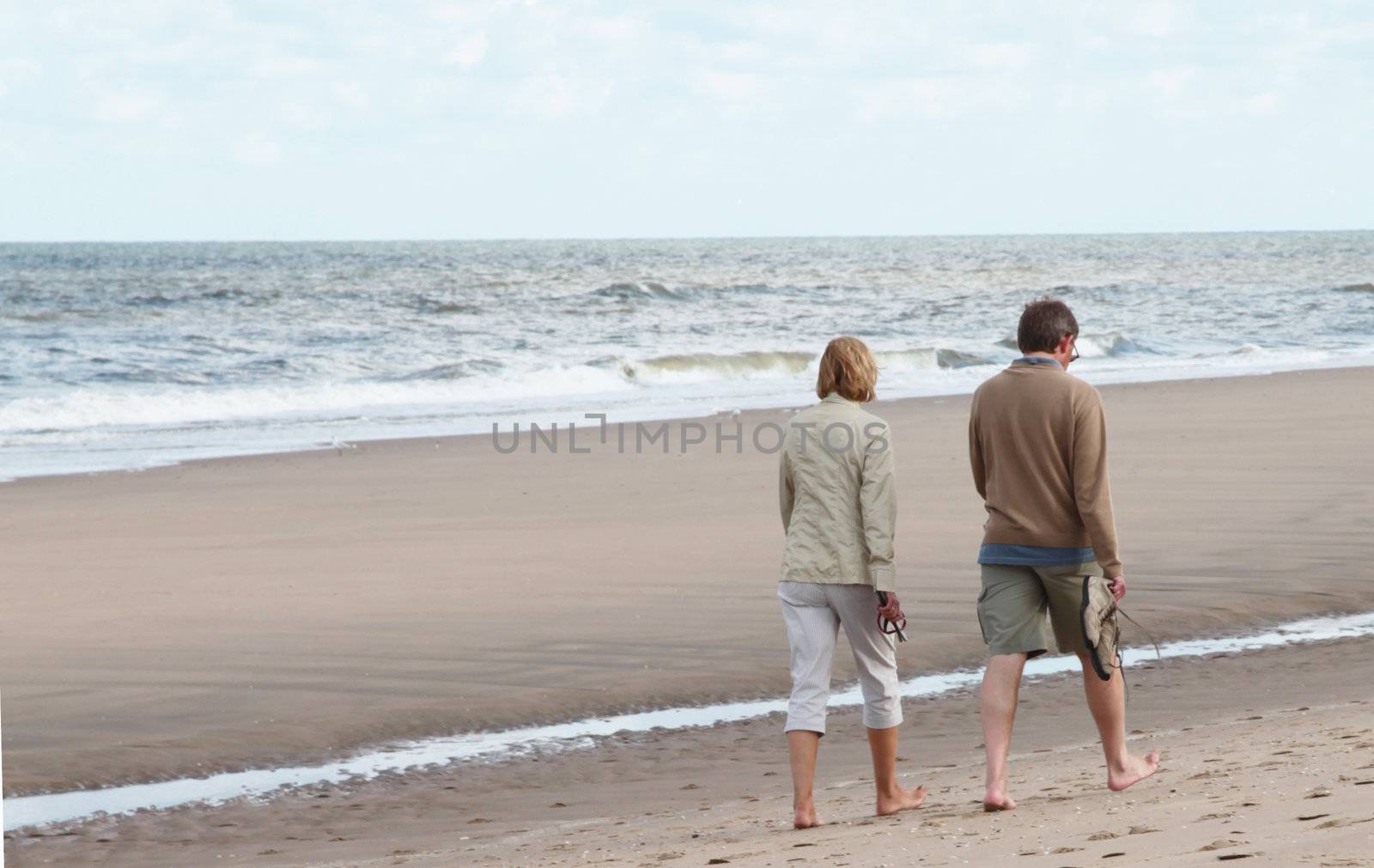 Middle aged man and woman taking a walk on the beach.