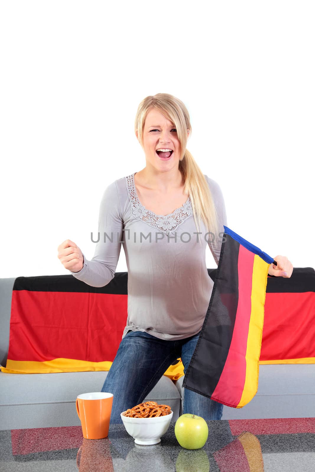 An attractive young woman whoops a German team while sitting at home and watching tv.